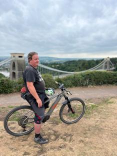 Man standing with his e-bike in front of Clifton Suspension Bridge.