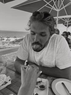 Black and white photo of a man sticking his tongue out while a woman shows him an engagement ring.