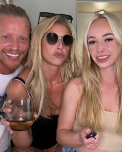 Three people smiling for a selfie; one woman holds a glass of wine.