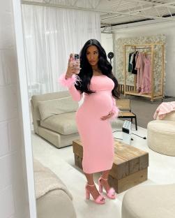 Pregnant woman in pink dress taking a selfie.