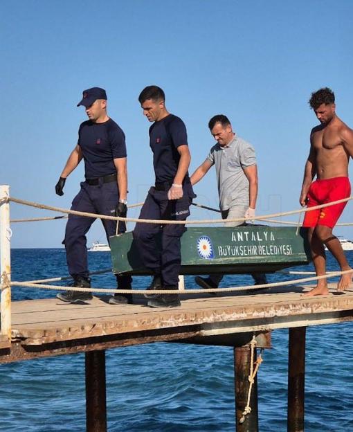 Four men carrying the body of Linariya Muzipova, 42, on a stretcher off a wooden pier in Kemer, Turkey.