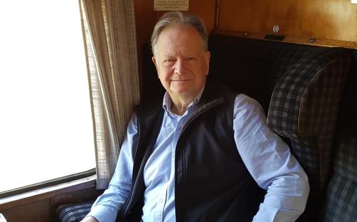 Steven Brookes MBE, Transport Policy Adviser for Disability Right UK, seated in a train carriage.