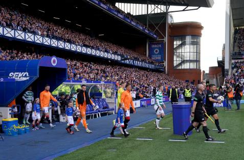 Rangers and Celtic players walking onto the pitch at Ibrox Stadium.