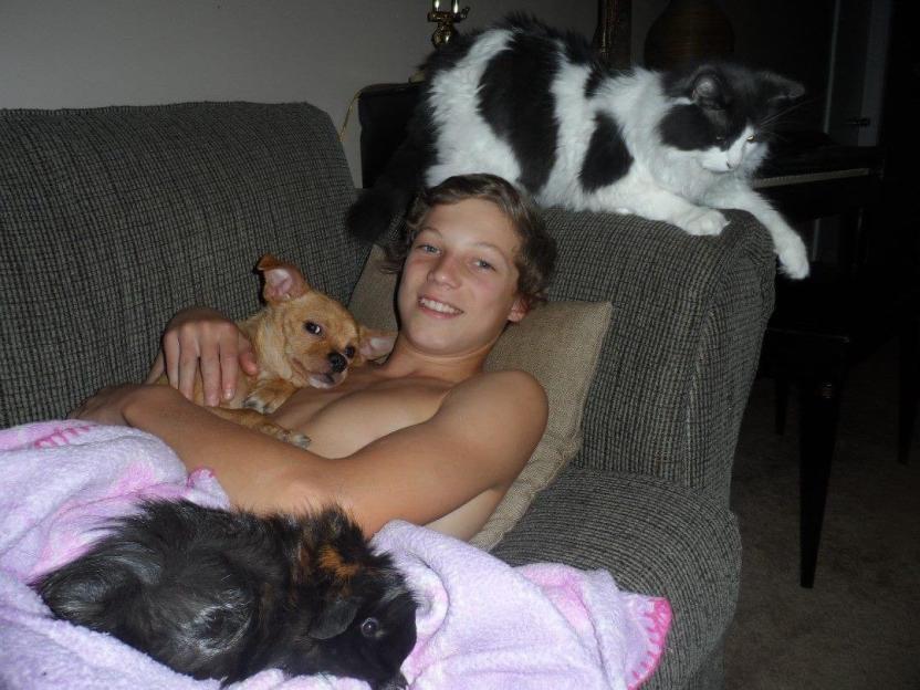 Matthew Eller on a couch with a chihuahua, guinea pig, and cat.
