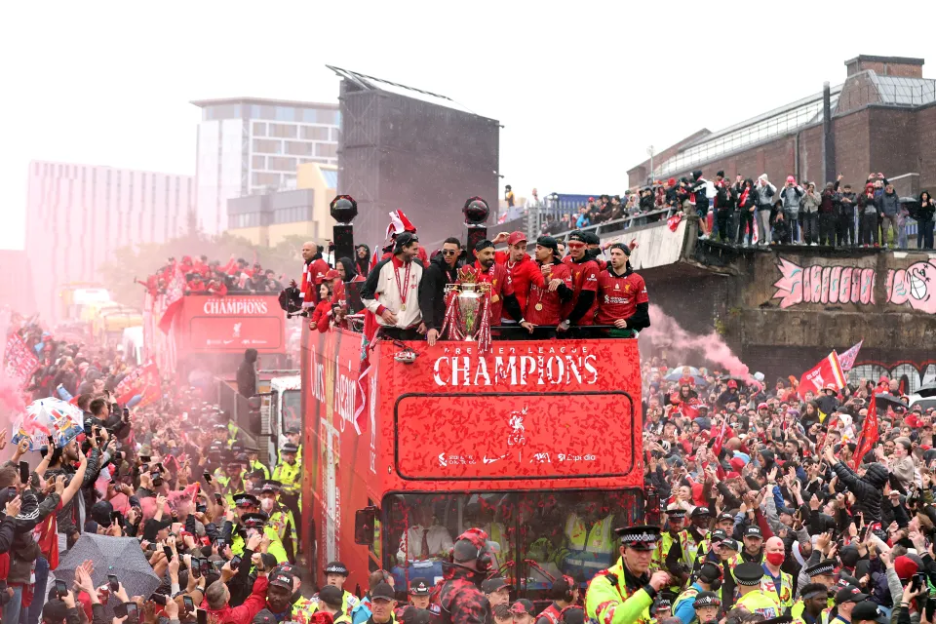Liverpool players celebrating Premier League victory on an open-top bus.