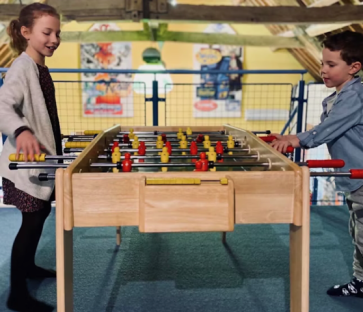 Two children playing foosball.