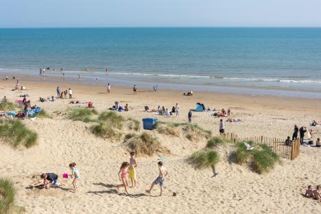 Beach scene with people swimming and relaxing on the sand.