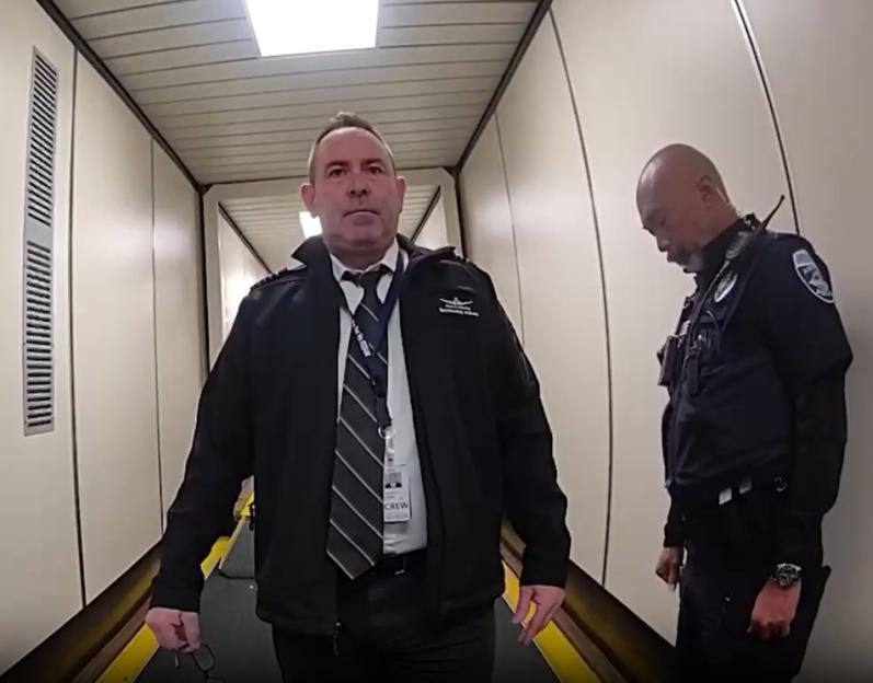 A pilot escorted by a police officer.