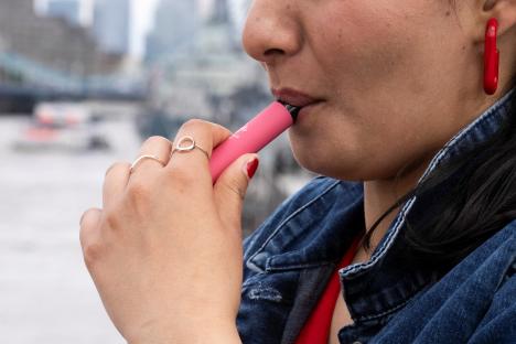 Person vaping a pink disposable vape.