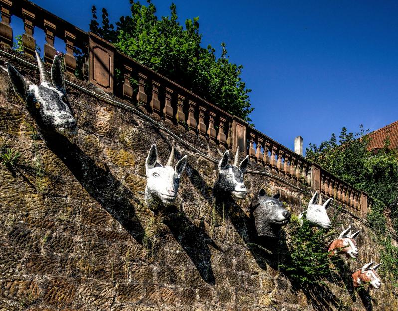 Sculptures of goats and a wolf on a stone wall.