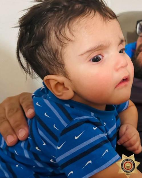 Photo of a baby in a blue shirt.