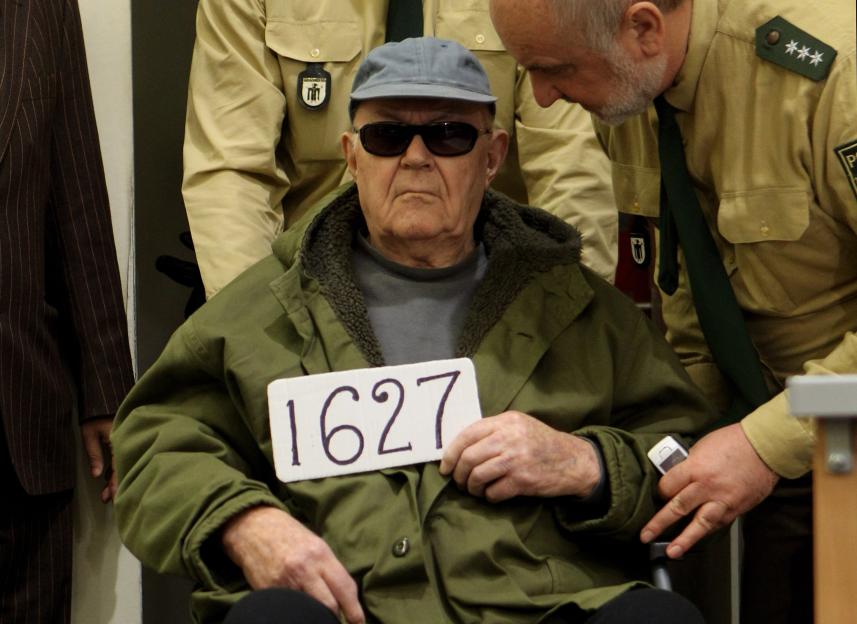 Accused Nazi criminal John Demjanjuk holding a sign with the number 1627 during his trial.