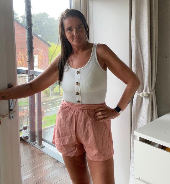 Woman in white top and pink shorts.