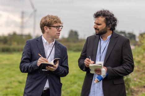 Josh Widdicombe and Nish Kumar taking notes outdoors.