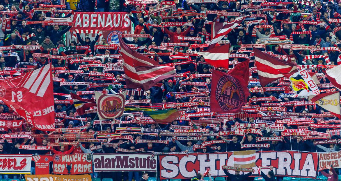 Bayern Munich fans with flags and banners at a soccer game.