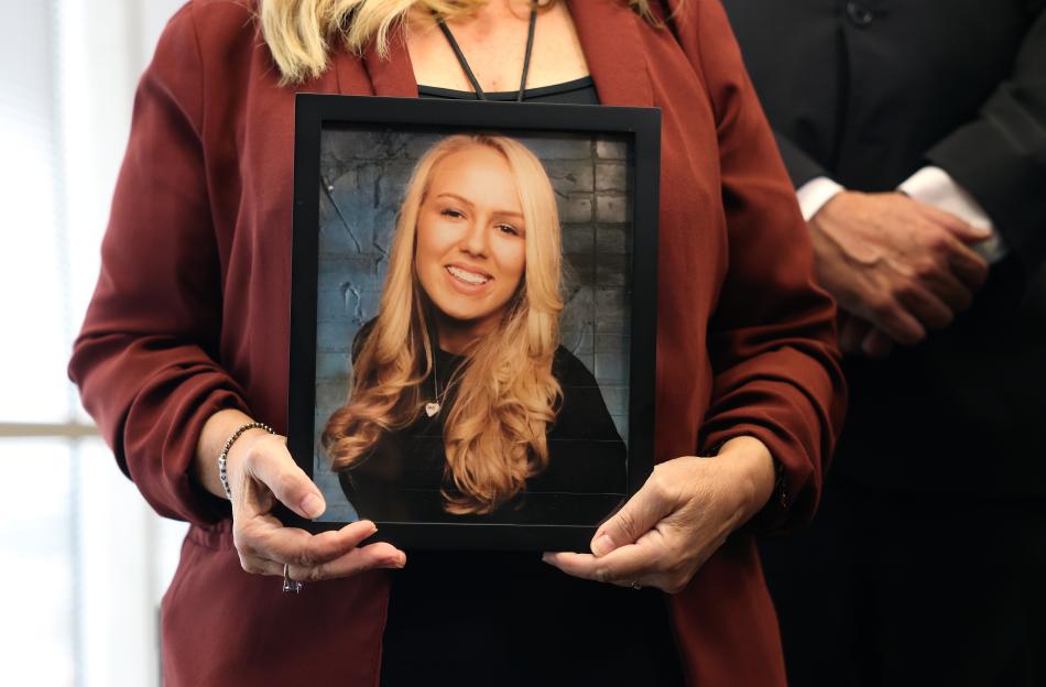 Woman holding framed photo of her daughter.
