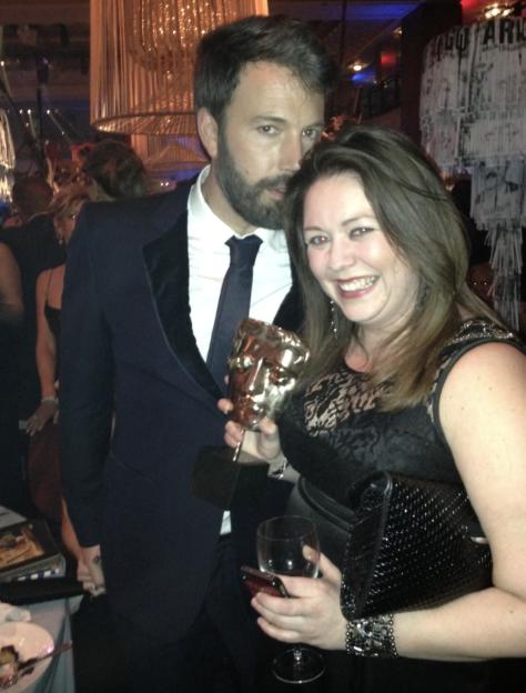 Kelly Allen holds a BAFTA award next to Ben Affleck.