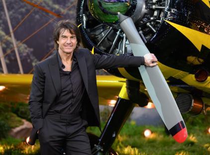 Tom Cruise at a premiere, leaning on a plane's propeller.