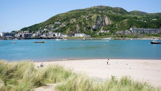 Beach at Penrhyn Point, Barmouth, with boats and a child playing on the sand.