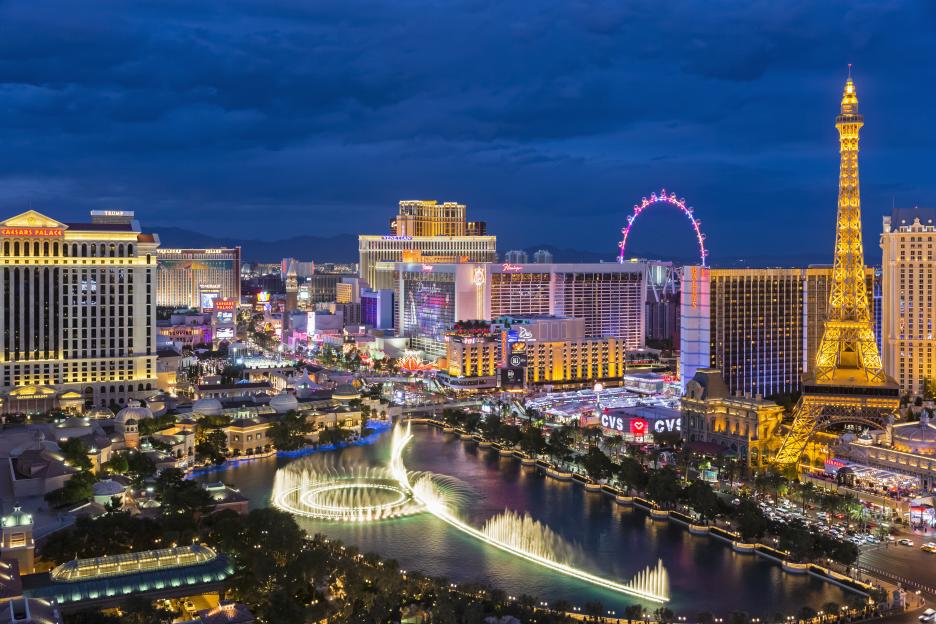 Las Vegas Strip at blue hour, with the Bellagio fountain, hotels like Caesars Palace and the Venetian, and the Eiffel Tower replica.