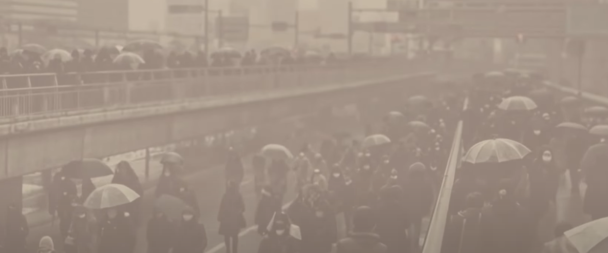 People with umbrellas walking in a foggy city.