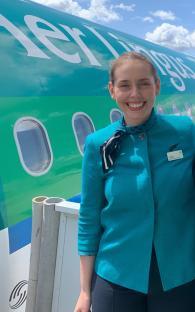 Aer Lingus flight attendant in uniform in front of an airplane.