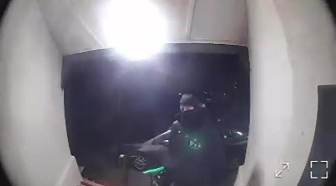 Video footage of an individual in dark clothing and a black face covering, possibly at the scene of the Peacehaven Mosque arson.