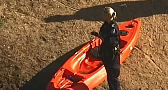 Police officer next to a red kayak.