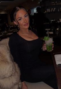 Woman in black dress holding a mojito.