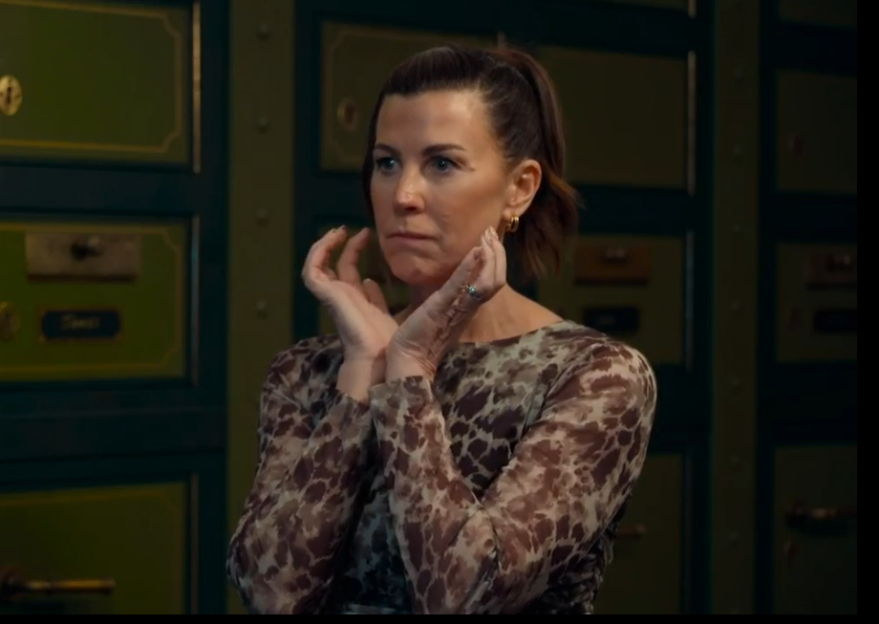 Woman in animal print dress with hands near face.