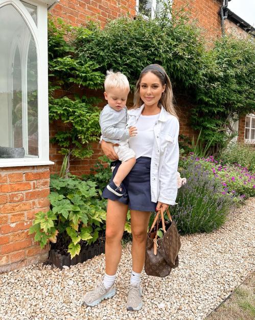 Woman holding toddler in front of house.