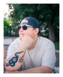 Man with sunglasses and a snake tattoo on his arm.