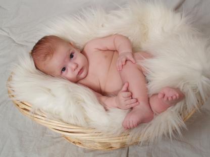 a baby is laying in a wicker basket on a white blanket
