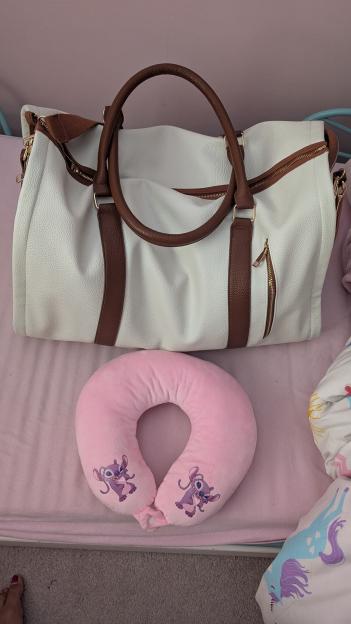 Cream faux leather holdall and pink neck pillow.