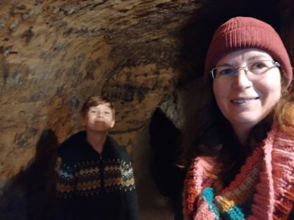 A woman and child exploring a dark tunnel.