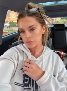 A young woman in a white hoodie sits in a car.