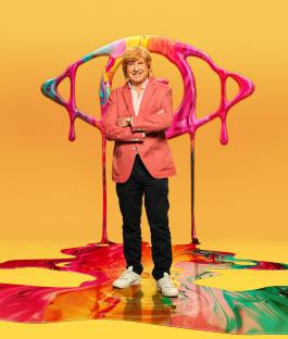 Michael Fabricant standing on a colorful paint spill with a large eye graphic behind him.