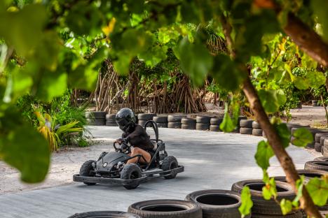 Person driving a go-kart on a tropical track.