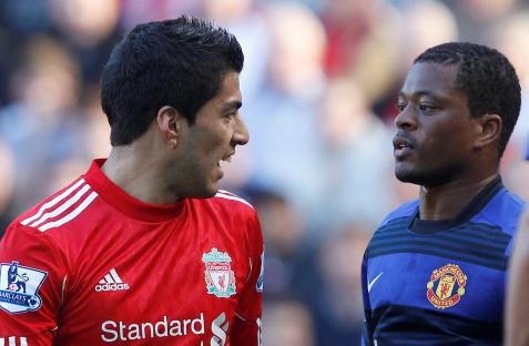 Luis SuÃ¡rez and Patrice Evra facing each other during a soccer match.
