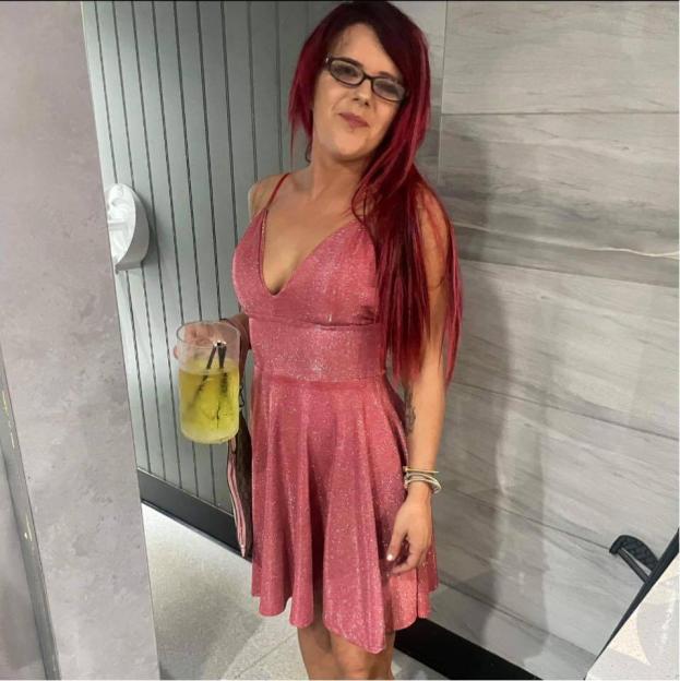 Woman in pink sparkly dress holding a drink.