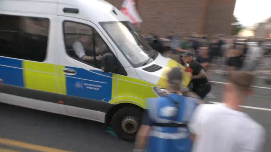 Police van driving through a crowd.