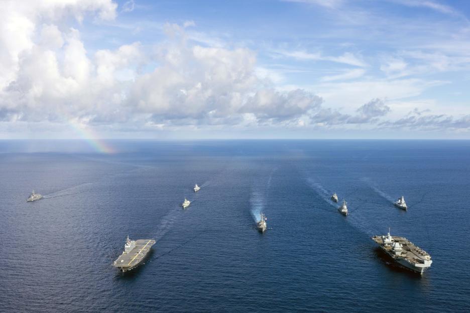 Aerial view of multiple naval ships sailing in formation.