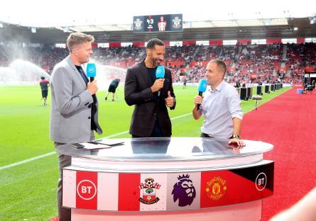 Three soccer pundits at a stadium, giving a report for BT Sport.