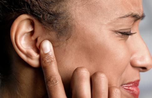 Woman touching her ear in pain.