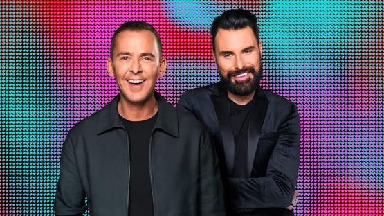 Two men smiling in front of a heart-shaped background.