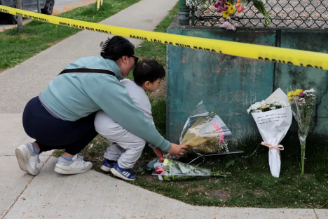 A woman and child place flowers at a memorial.