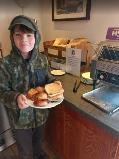 Boy holding a plate of breakfast food.