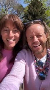 Close-up photo of a smiling couple wearing pink sweaters.