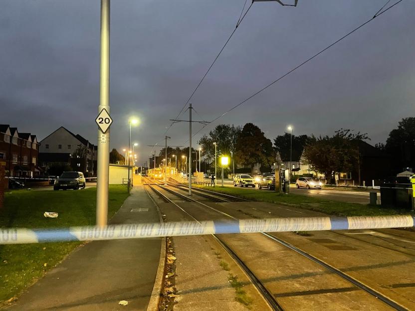Police tape across tram tracks at night on Brownley Road/Crossacres Tram Stop, with emergency services visible in the background.