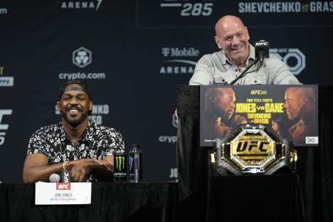 jon jones sits at a table next to dana white